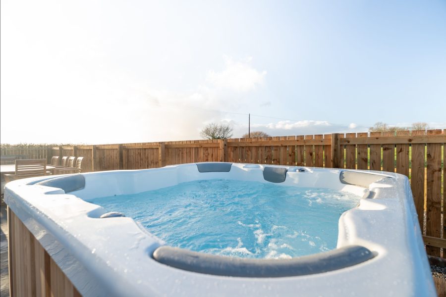 Outdoor hot tub at Wheatsheaf Barn, a self-catering holiday cottage, set within a fenced private area.