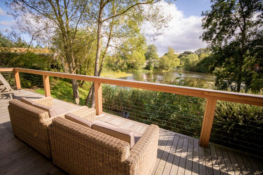 Decking of Imogen lodge at Brompton Lakes with outdoor seating and lakeside views.
