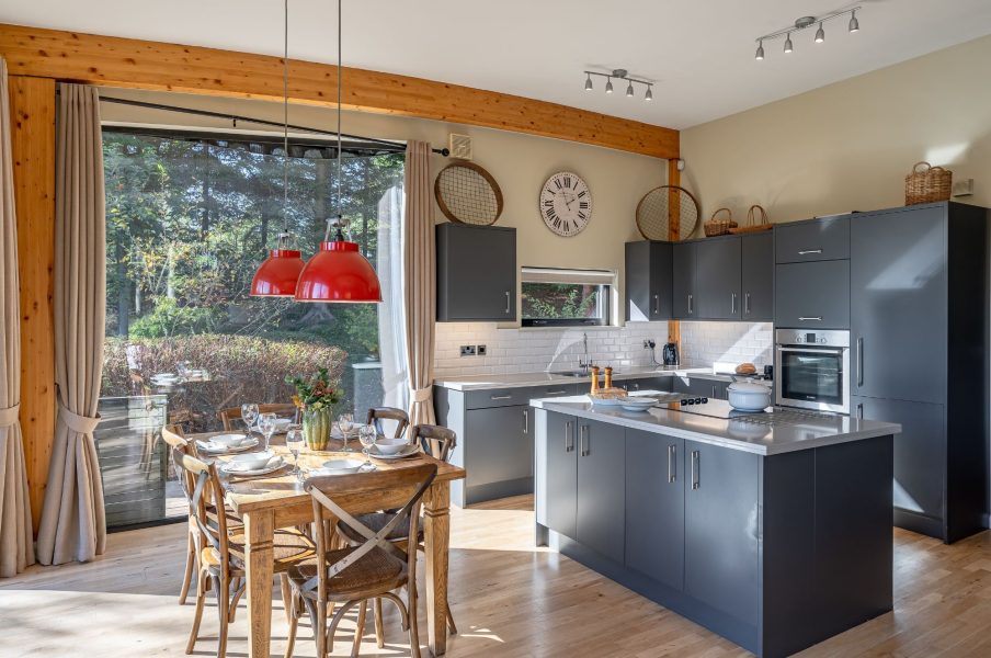 Open-plan kitchen at Imogen lodge at Brompton Lakes with island, modern appliances, and dining area with garden views.