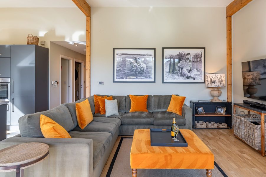 Modern living room at Imogen lodge at Brompton Lakes with large sofa, artwork and wall-mounted TV.
