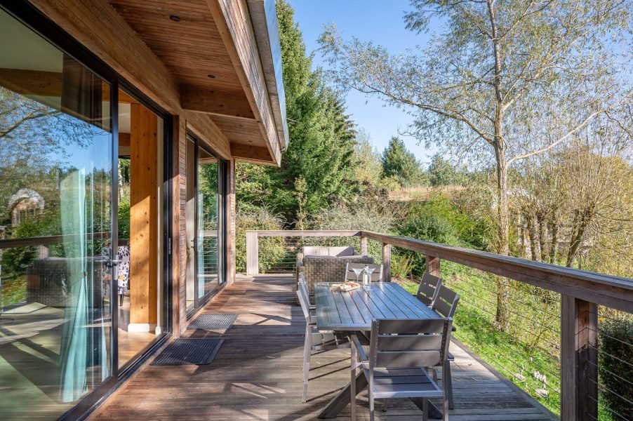 Outdoor decking area of Imogen lodge at Brompton Lakes with dining table, chairs, and scenic lake view.