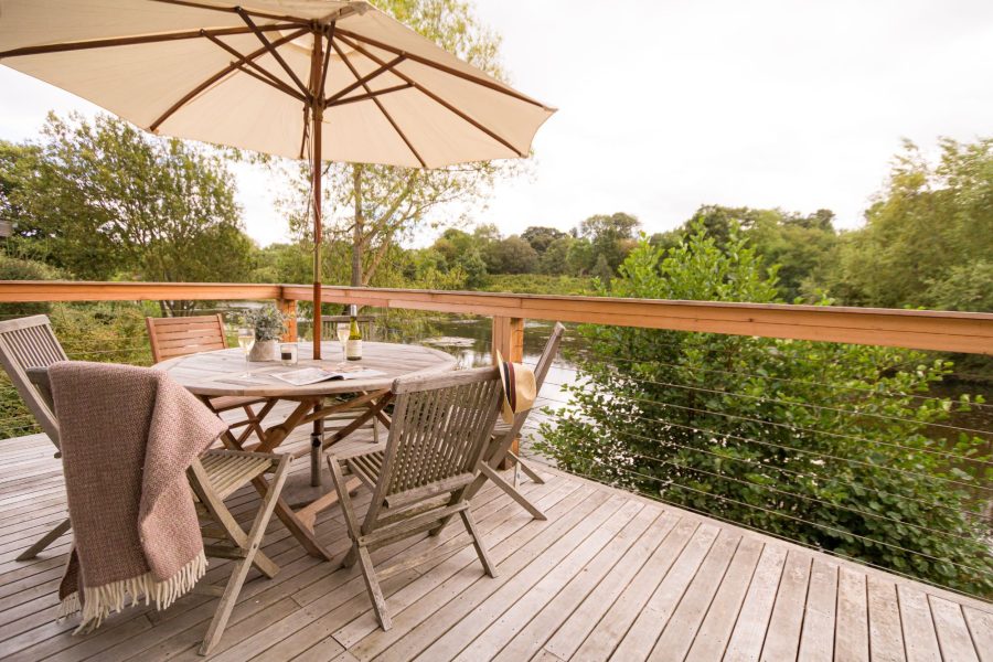 Private deck at Jasper lodge with outdoor dining table overlooking tranquil lake at Brompton Lakes, Yorkshire. 