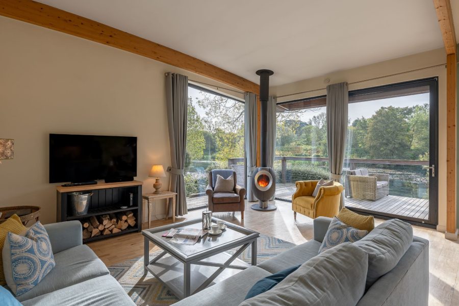 Cosy living room in Jasper lodge with sofas, TV, wood-burning stove and lake views.