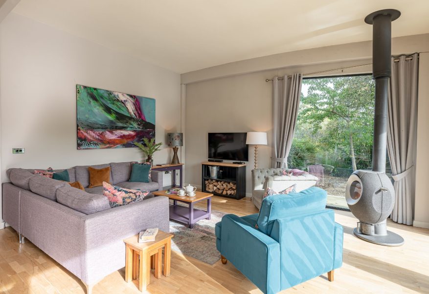 Cosy lounge with sofa, armchairs and log burner and lakeside views in Finley lodge.