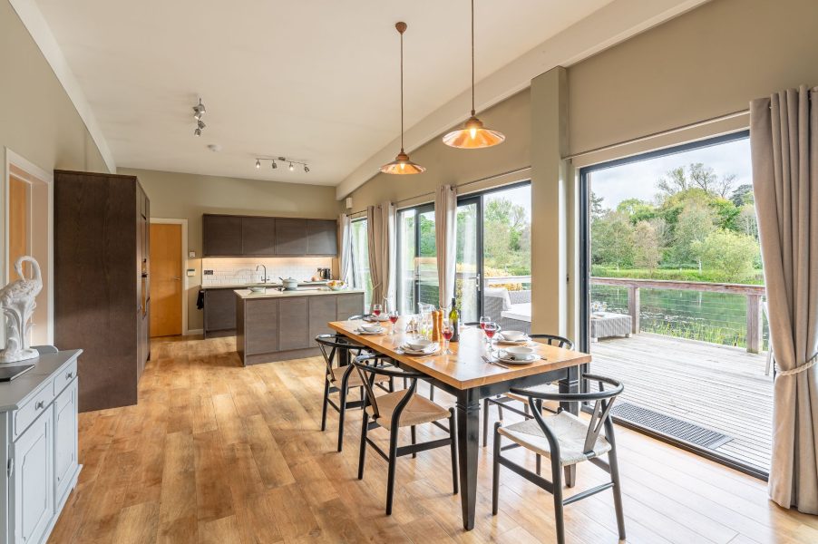 Spacious open-plan living area in Juniper lodge at Brompton Lakes with dining table and access to lakeside decking.