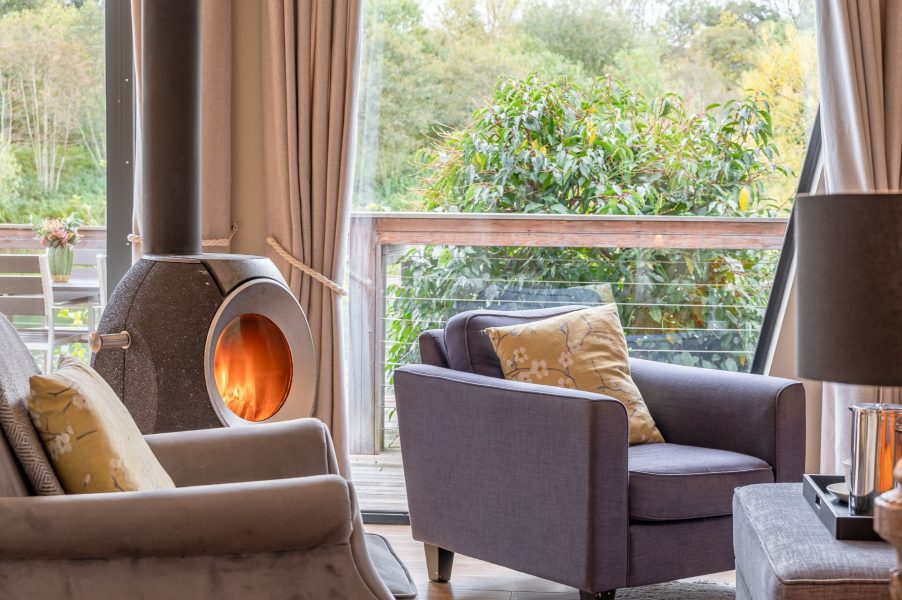 Cosy living room with wood-burning stove and panoramic lake views in Juniper lodge, Brompton Lakes.