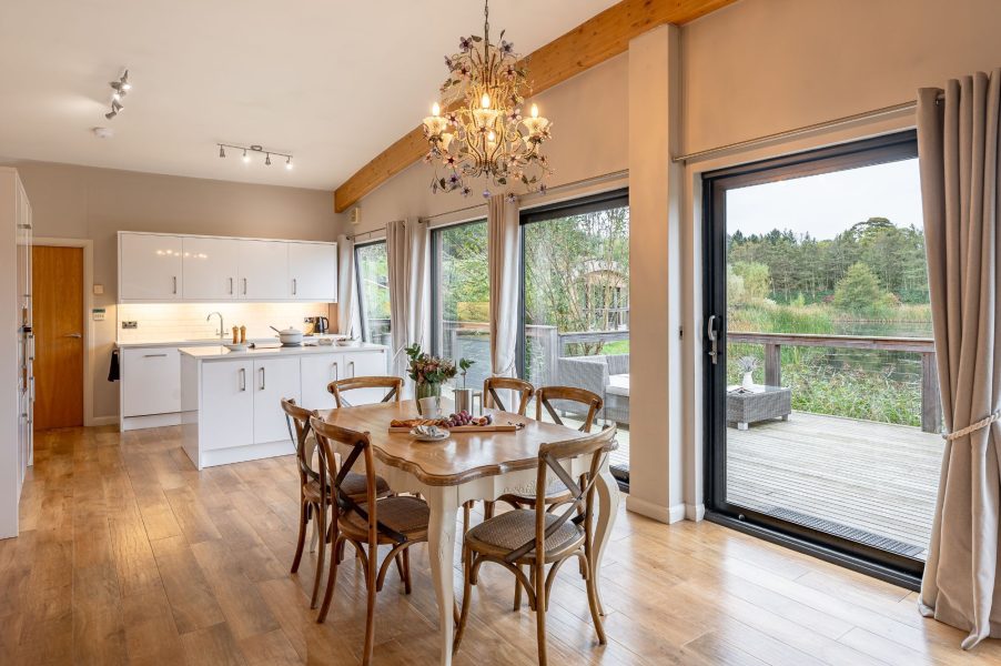 Spacious dining area in Charlie lodge with large windows overlooking Brompton Lakes.