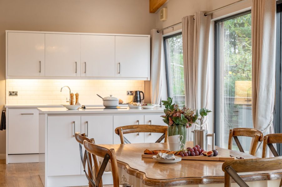 Open-plan kitchen and dining area in Charlie lodge at Brompton Lakes with modern appliances and large windows. 