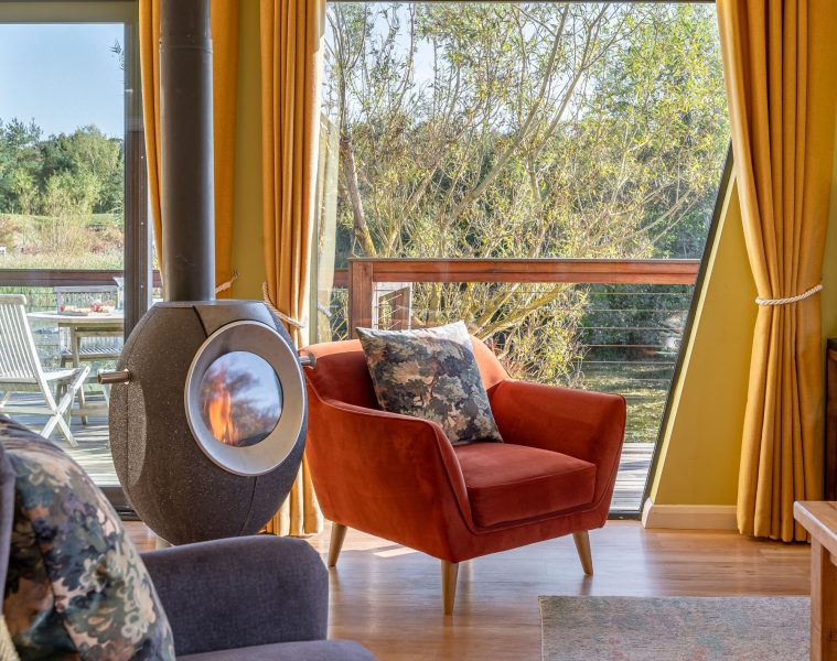 Cosy living area with log burner in Florence lodge at Brompton Lakes with lakeside views.