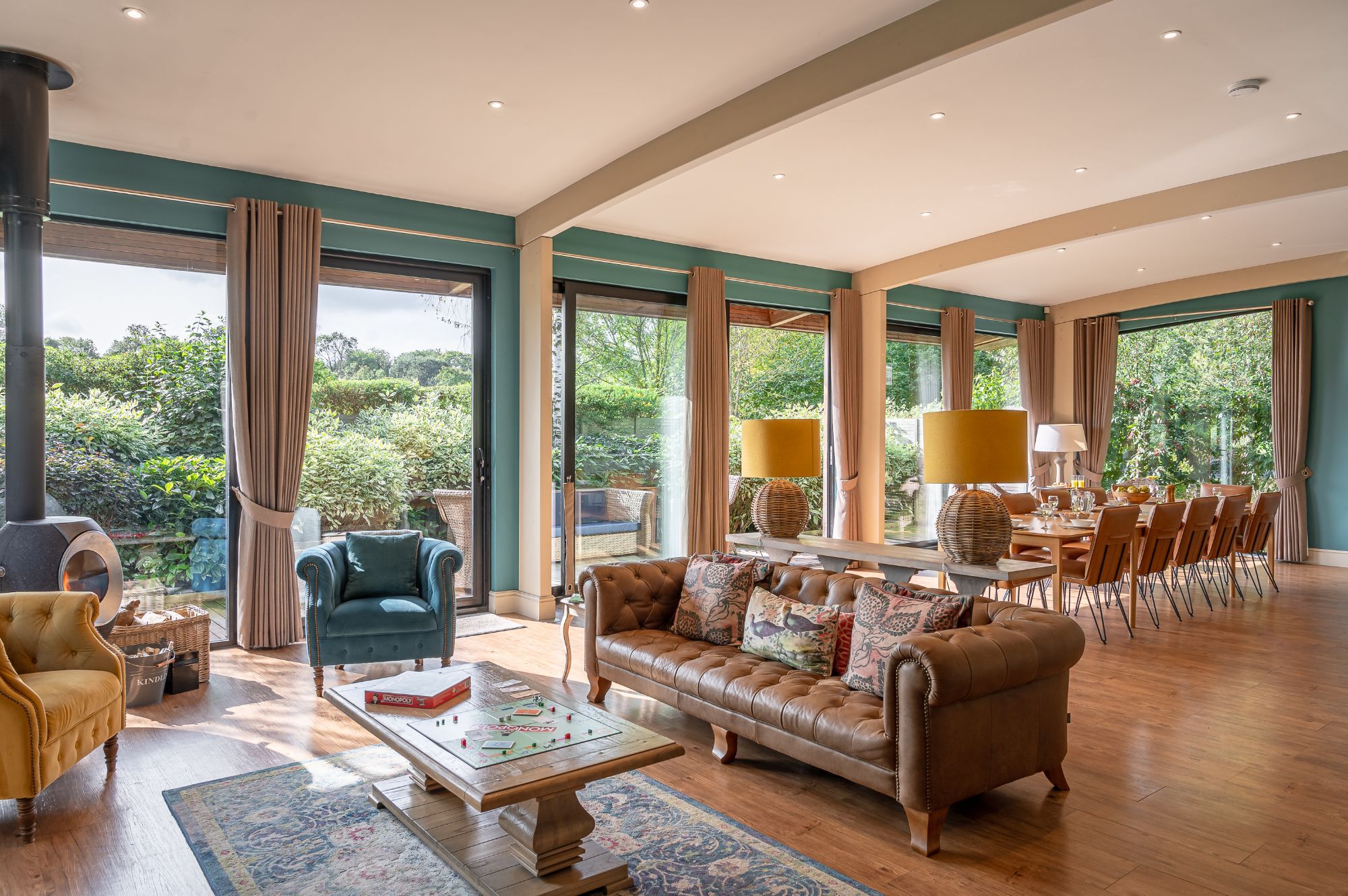 Bright living area of Twenty One lodge with large sofa, armchairs, dining table and garden views at Brompton Lakes, North Yorkshire.