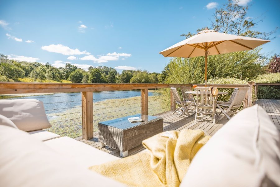 Private deck at Louis lodge with outdoor dining table, parasol and countryside views at Brompton Lakes.