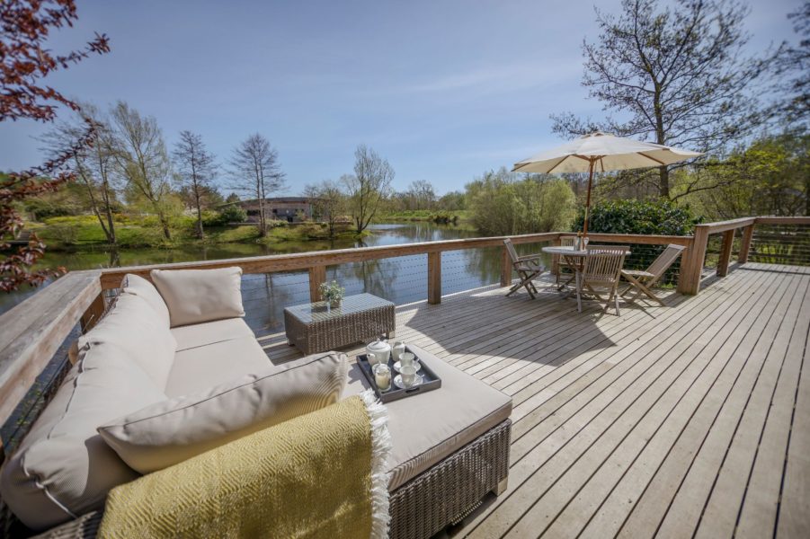 Spacious private deck at Abbey, featuring outdoor lounge seating and dining with tranquil views across the lake.