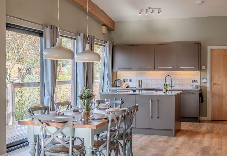 Open-plan kitchen and dining area in Rebecca lodge at Brompton Lakes with lake views and private decking.
