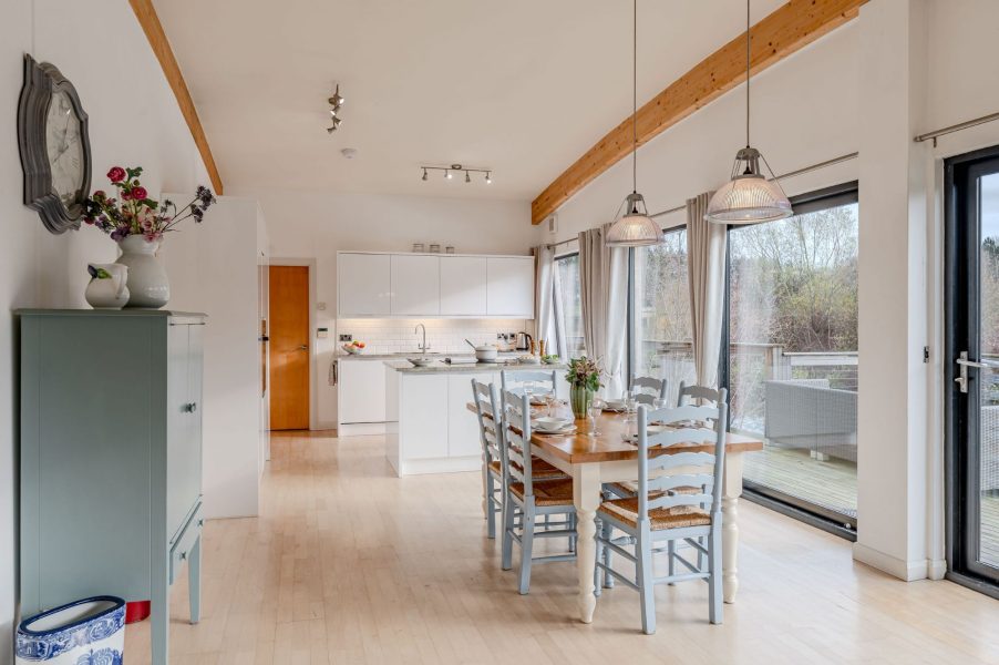 Open-plan kitchen and dining area in Lulu lodge, Brompton Lakes with high ceilings and large glass doors to decking.