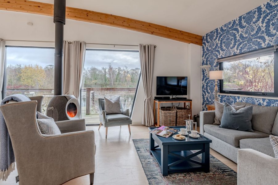 Cosy living area in Lulu lodge, Brompton Lakes with wood burning stove, armchairs and lake views.