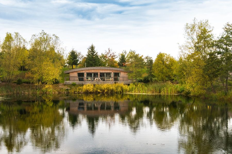 Lola lodge exterior reflected in lake at Brompton Lakes, Yorkshire.