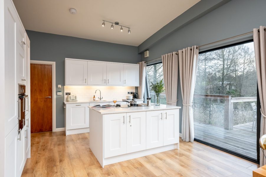 Open-plan kitchen with island and floor-to-ceiling windows and lake views at Brompton Lakes, Yorkshire.