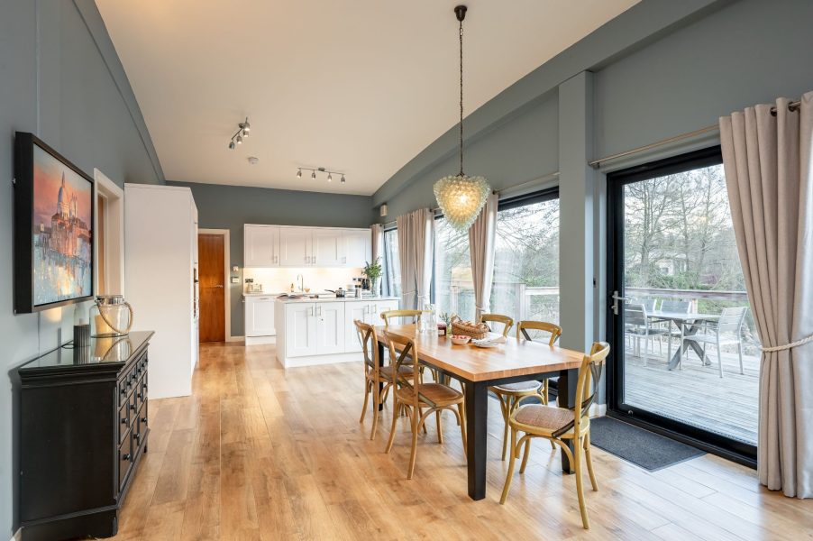 Open-plan living and dining area with floor-to-ceiling windows and lake views at Brompton Lakes, Yorkshire.