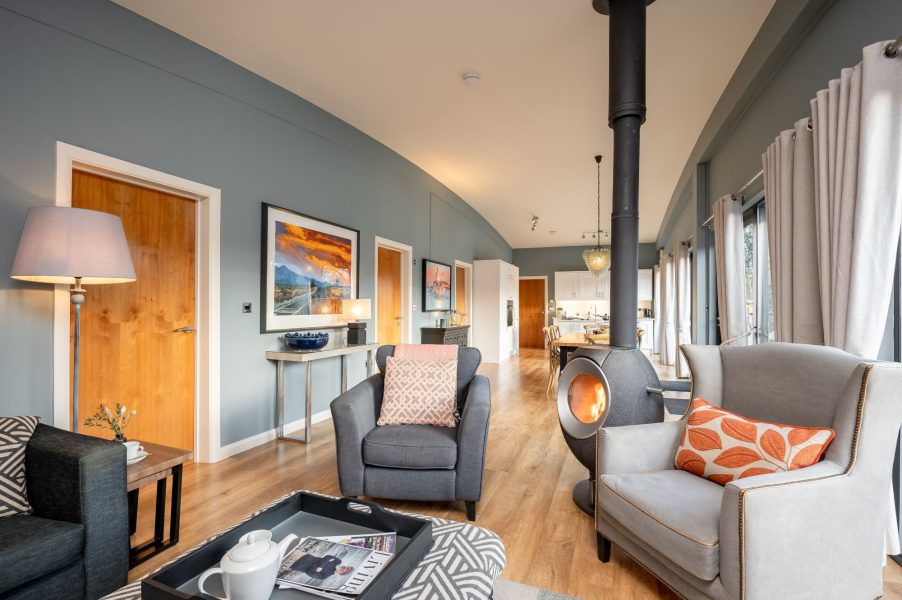 Open-plan living area in Lola lodge with log burner and lake views at Brompton Lakes, Yorkshire.