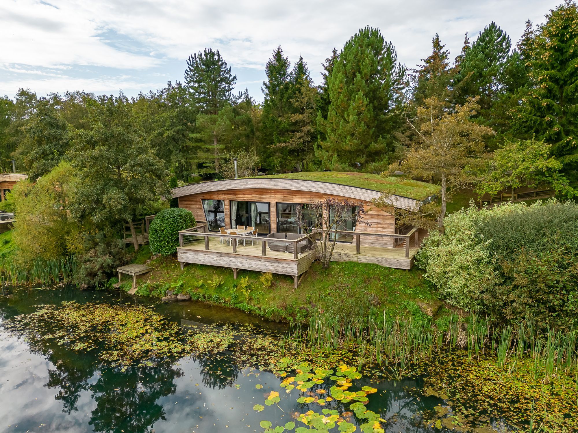 Exterior view of Abbey, a lakeside lodge with a large private deck overlooking the water and surrounding woodland.