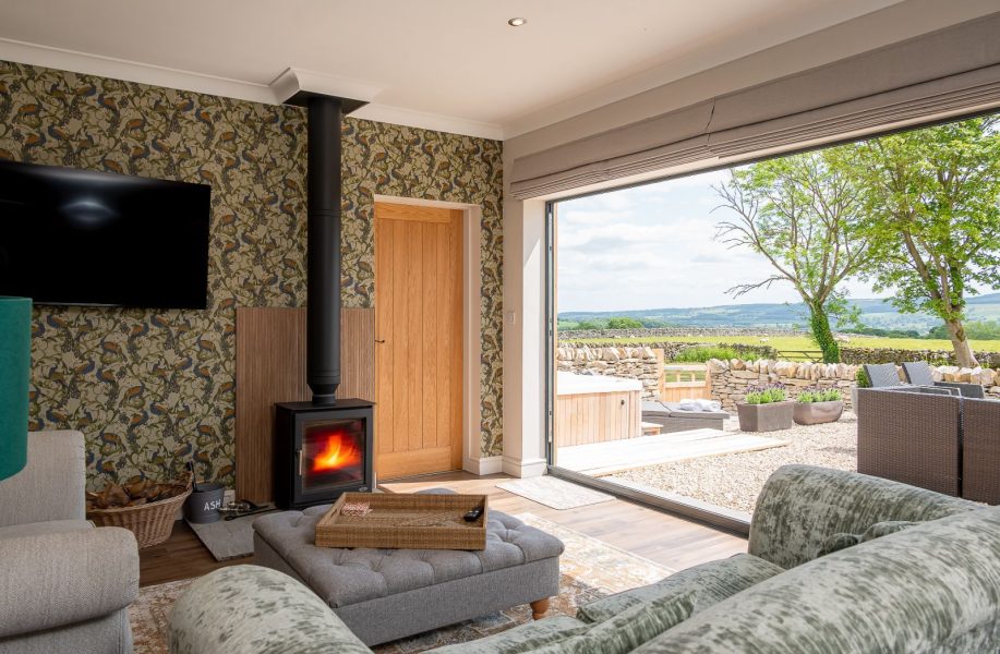 Living room in The Stables, North Yorkshire with wood-burning stove and bi fold doors to private patio and countryside views.