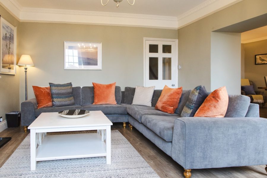 Living room at 30 Frenchgate with a corner sofa, coffee table, floor lamp, wall art, and doorway to another room.