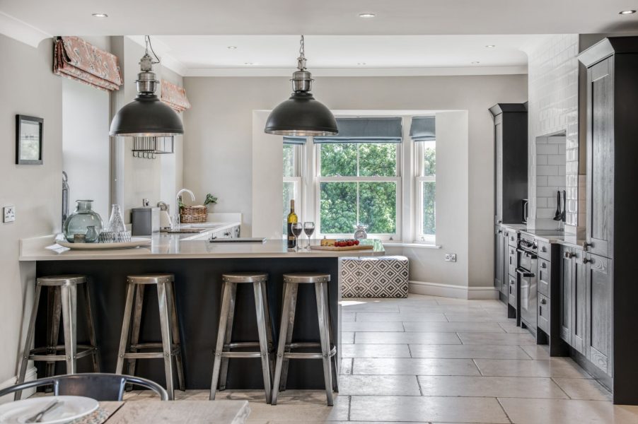 Modern farmhouse kitchen at The Farmhouse at Greenbank Barns with breakfast bar, bar stools, pendant lighting and large windows.