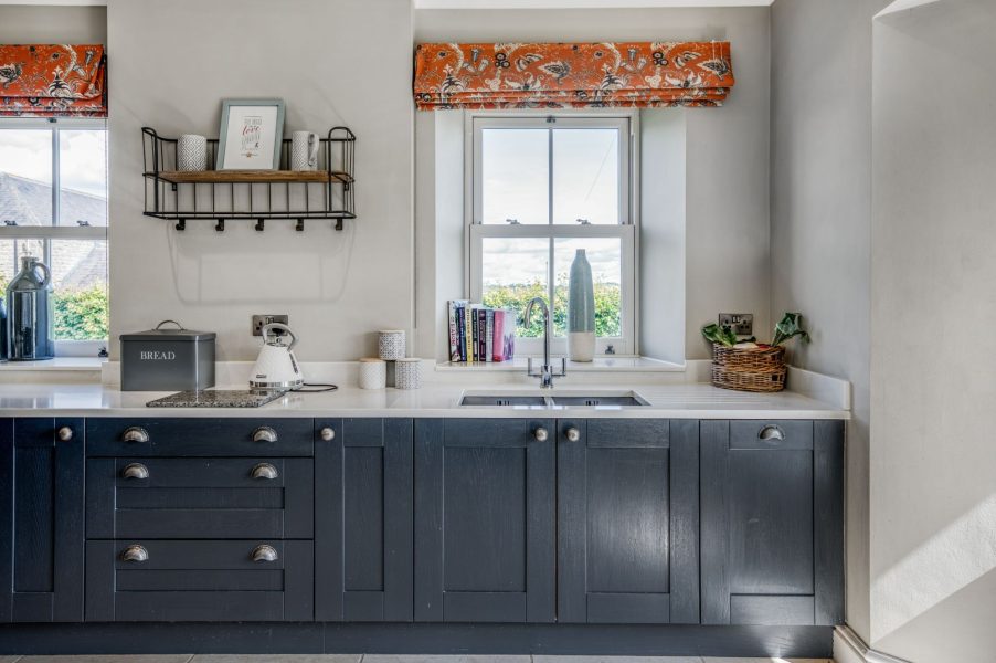 Modern farmhouse kitchen at The Farmhouse at Greenbank Barns with integrated appliances and large windows.