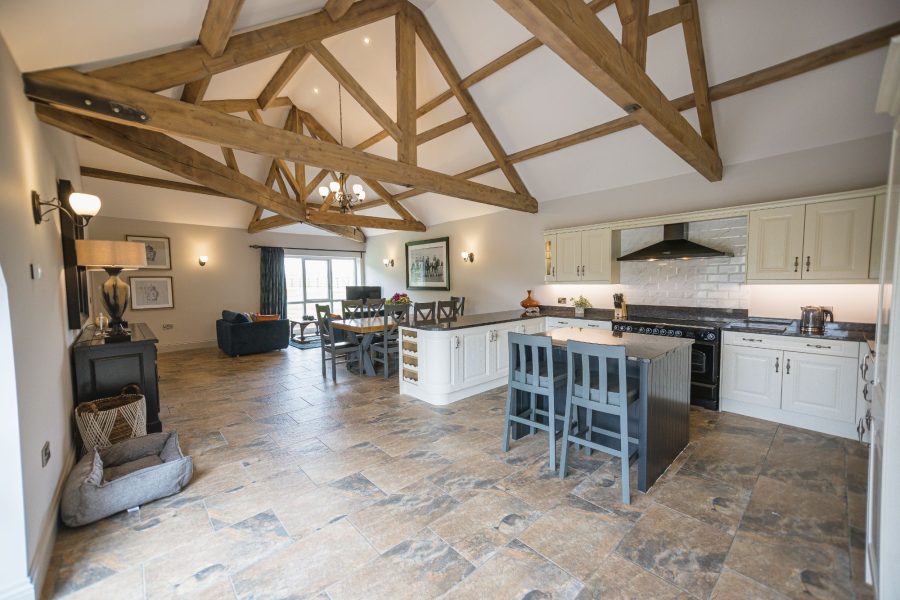 Open-plan living, dining and kitchen area at Kingfisher holiday cottage with exposed beams.