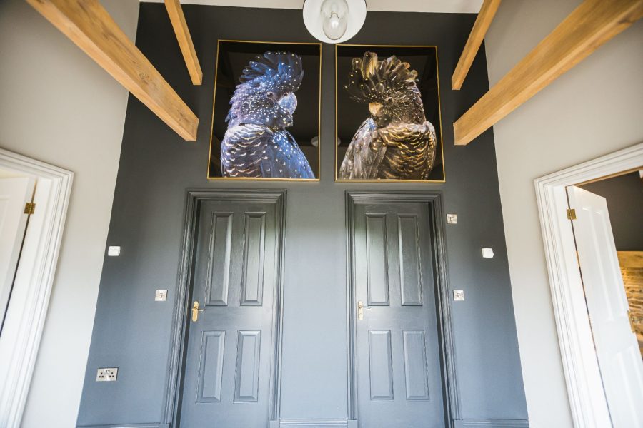 Stylish hallway in Kingfisher holiday home with dark feature wall and decorative artwork.