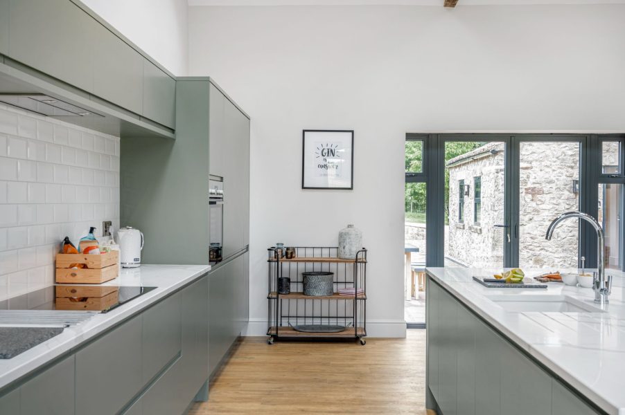 Modern kitchen with sage green cabinets and island in Dragonfly, a luxury holiday cottage in North Yorkshire.