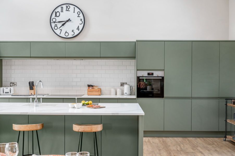 Spacious kitchen with breakfast bar, modern appliances and green cabinetry in Dragonfly cottage.