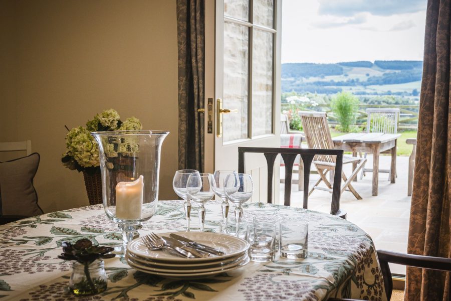 Large dining area with doors opening to patio and countryside views at Hollins Farmhouse.