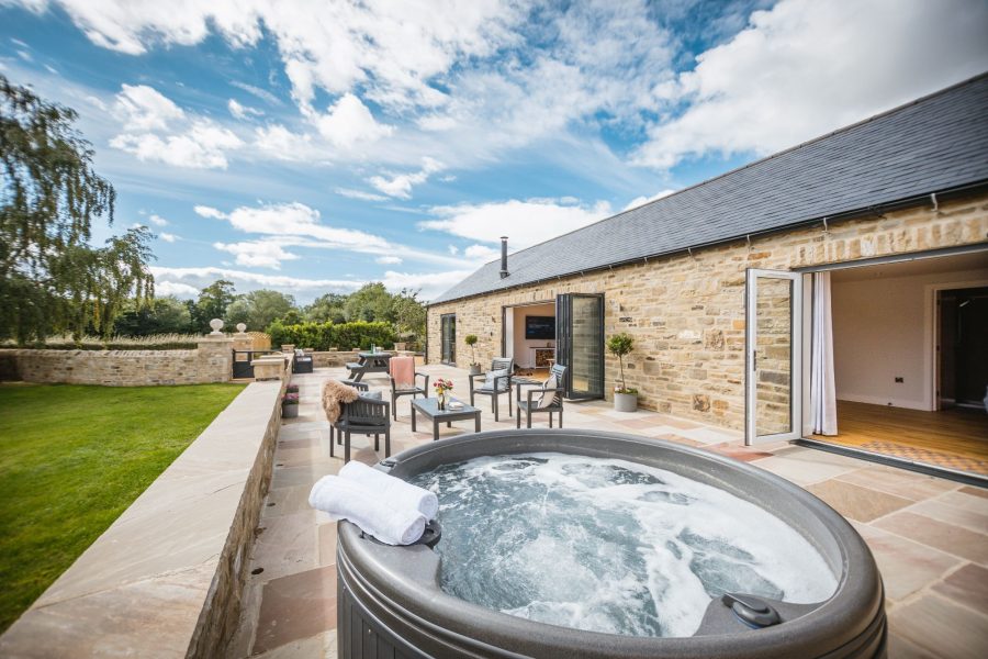 Private patio with hot tub, outdoor seating and countryside garden views at Millfield Barn.