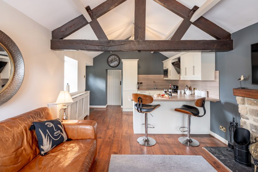 Open-plan kitchen and living area with breakfast bar, exposed beams and modern appliances at Sun Hill Palins.