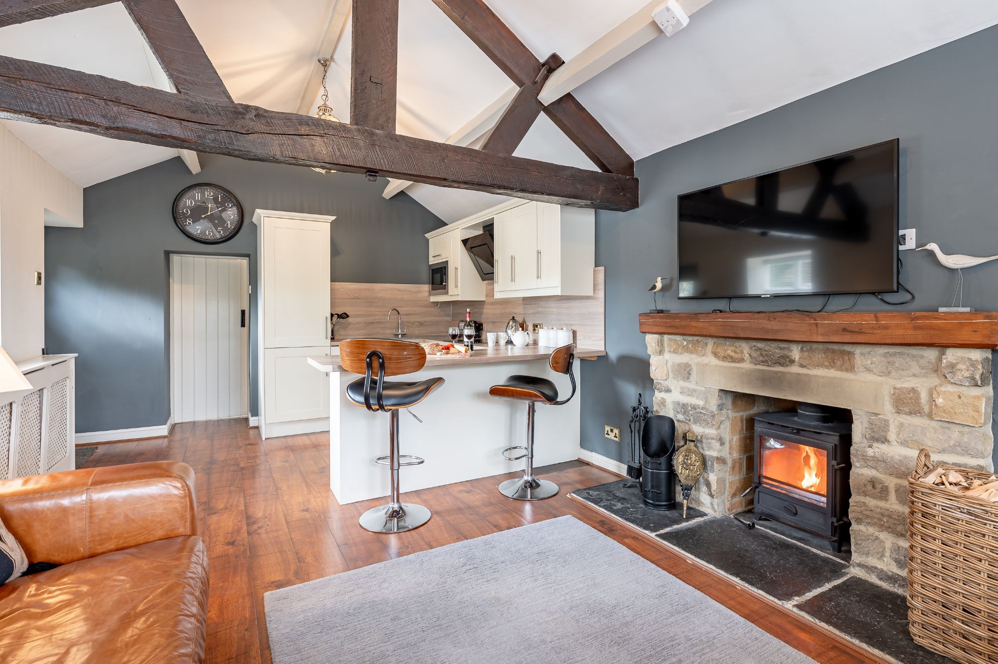Open-plan kitchen and living area with breakfast bar, exposed beams and log burner at Sun Hill Palins.