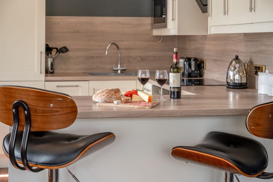 Modern kitchen with breakfast bar seating at Sun Hill Palins. 