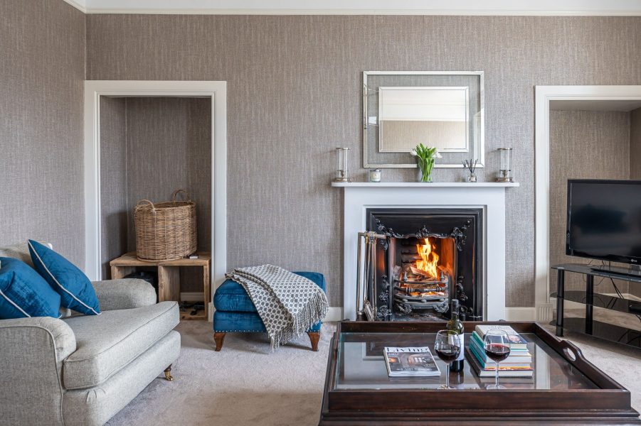 Porte House living room with open fireplace, coffee table and comfortable seating area.