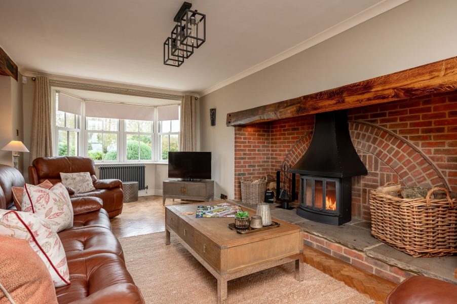 Cosy living room with wood-burning stove and exposed beams at Harelands holiday cottage.