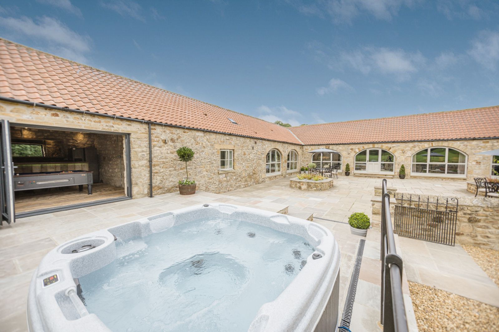 Luxury hot tub in private courtyard at Kingfisher cottage with surrounding stone buildings.