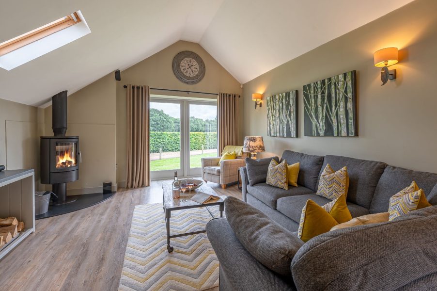 Spacious open-plan living room with sofa, coffee table, wood burner and garden views in Austin holiday cottage.