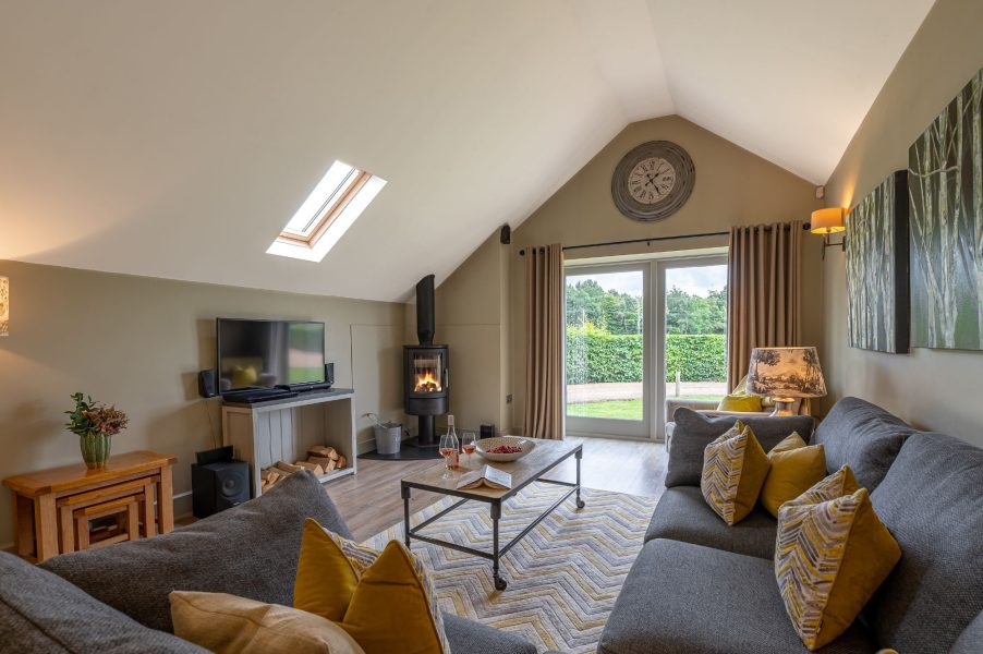 Spacious open-plan living room with sofa, coffee table, wood burner and garden views in Austin holiday cottage.