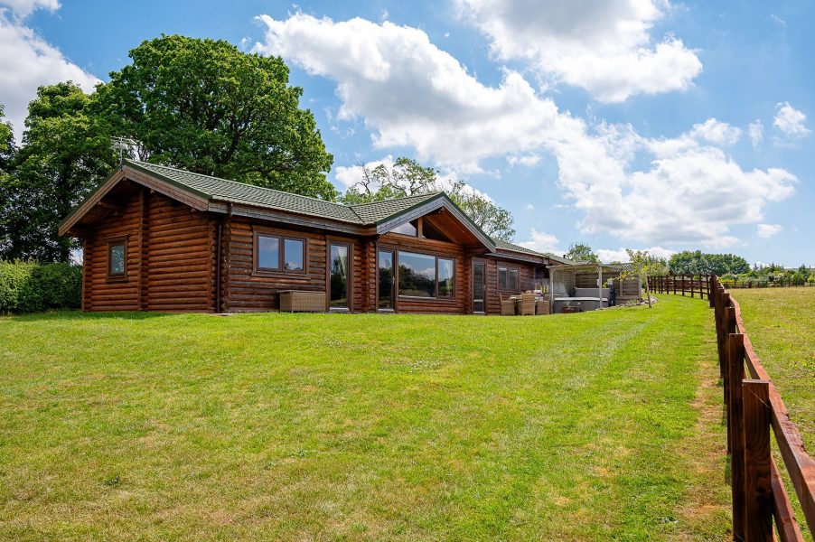 Exterior of  Constable Burton , a wooden log cabin at Sun Hill Lodges with patio, garden lawn and countryside views.