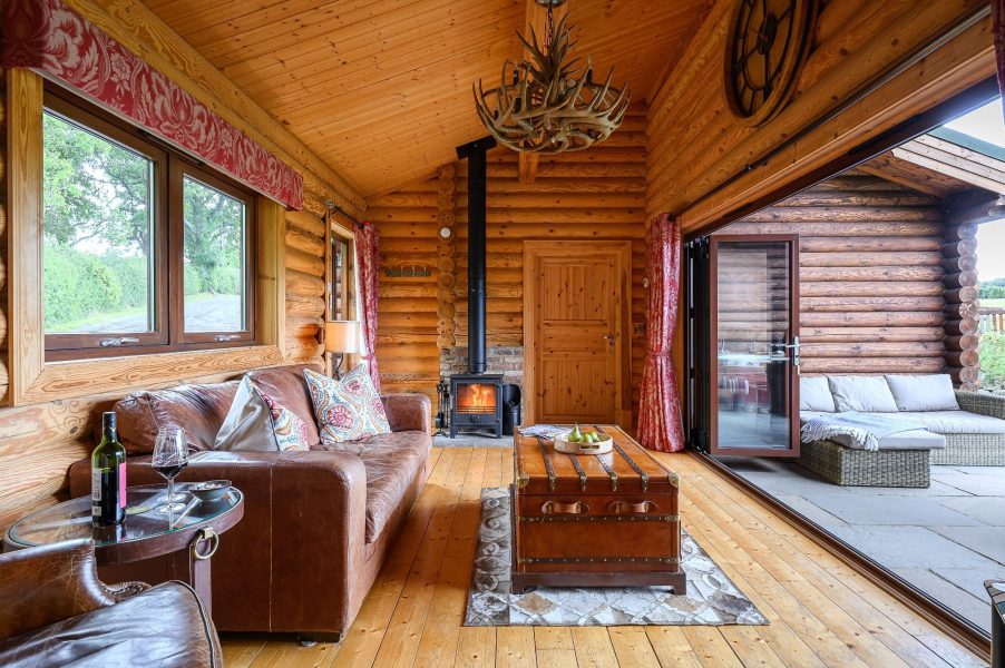 Open-plan living space at Hunters Lodge with wood-burning stove and patio doors.