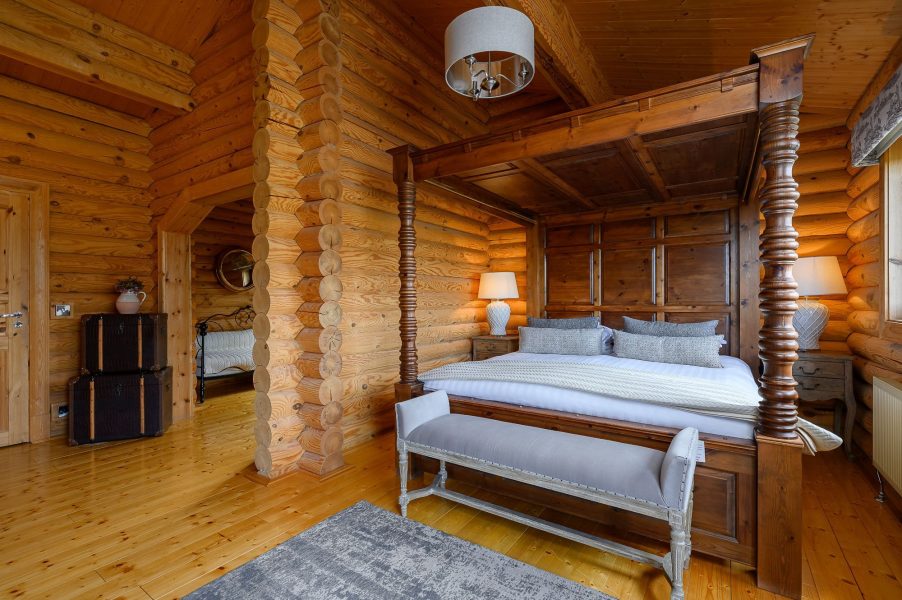 Spacious log cabin bedroom in Rosina lodge with four-poster bed and log cabin interiors.