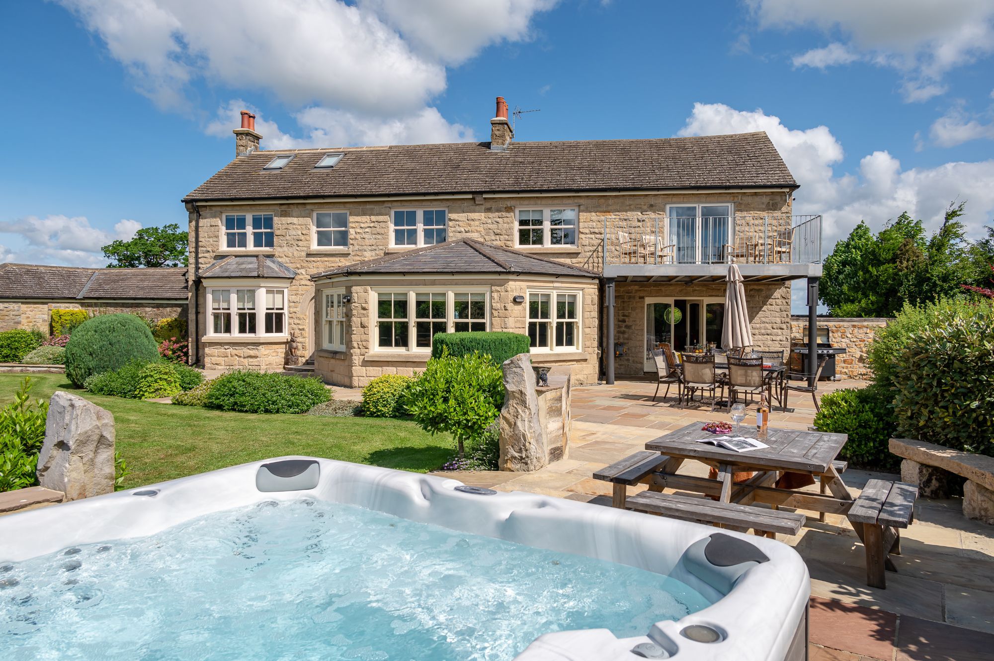 Harelands holiday cottage exterior with landscaped garden, outdoor seating and private hot tub in North Yorkshire countryside.