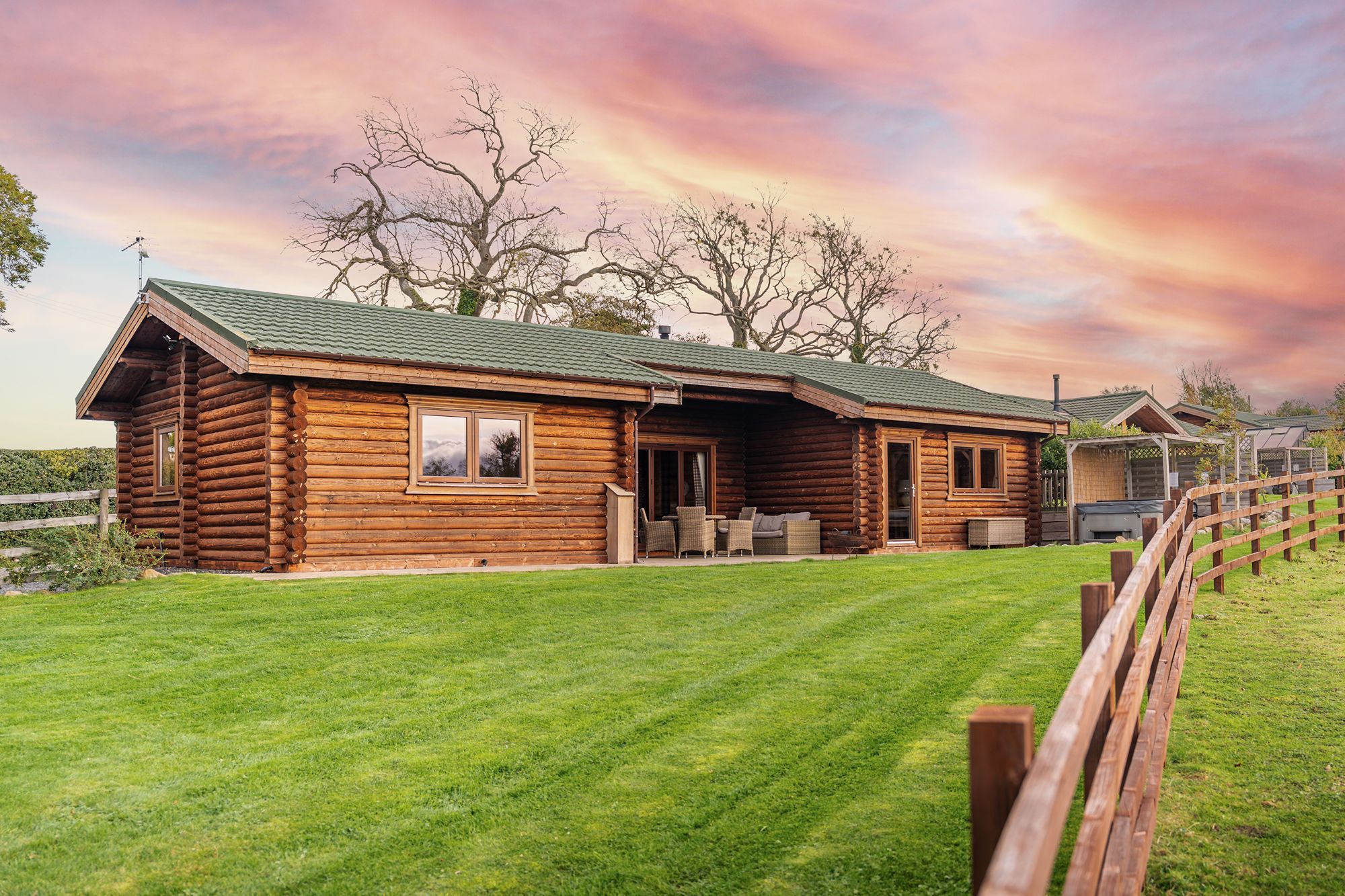 Exterior of Hunters Lodge, a wooden log cabin with patio, garden lawn and countryside views at Sun Hill Lodges.
