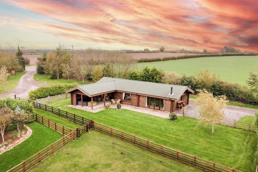 Exterior of Melody lodge, a wooden log cabin with patio, garden lawn and countryside views at Sun Hill Lodges.