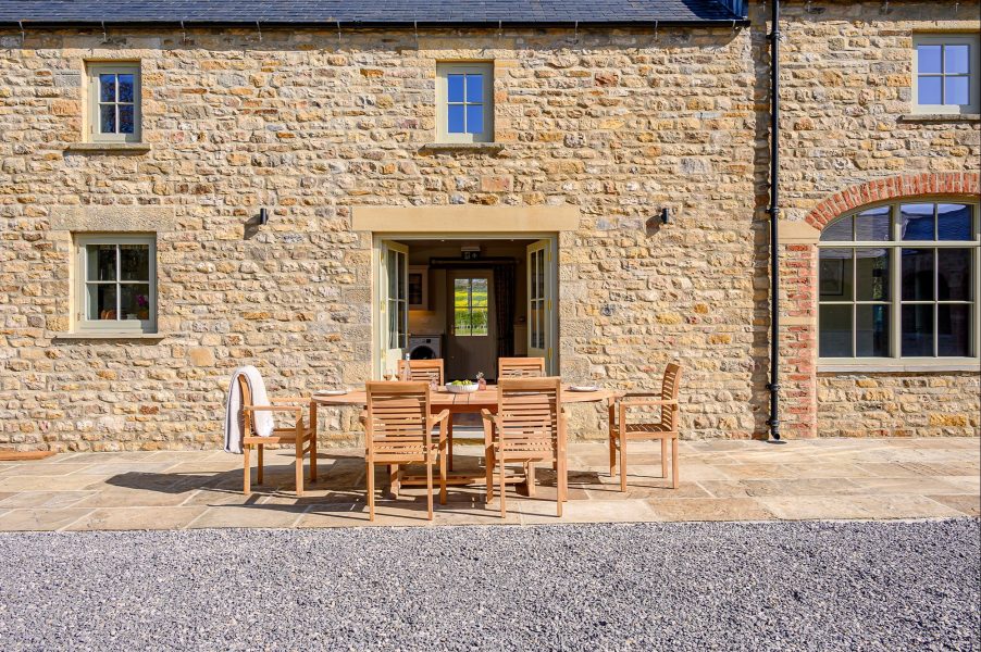 Hollins Barn in North Yorkshire, a luxury stone barn with outdoor dining area and traditional Yorkshire architecture.