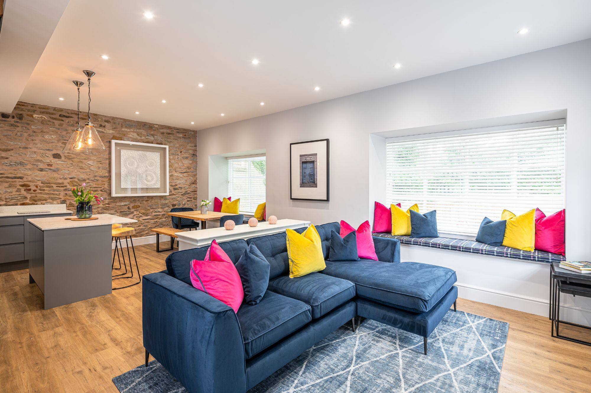 Modern open-plan living area with blue sofa and colourful cushions in The Old Tack Room.